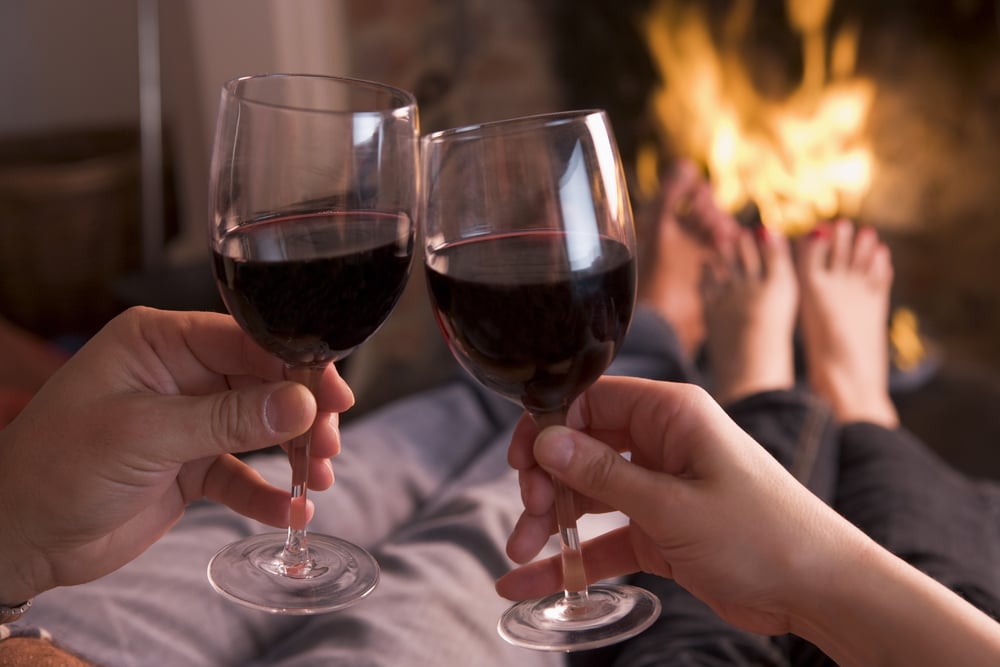 Couple sharing a glass of wine by the fire during the most romantic getaways in Minnesota